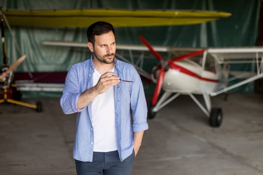 Handsome young pilot checking ultralight airplane before flight