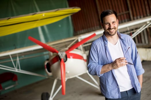 Handsome young man in the airplane hangar