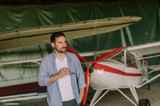 Handsome young man in the airplane hangar