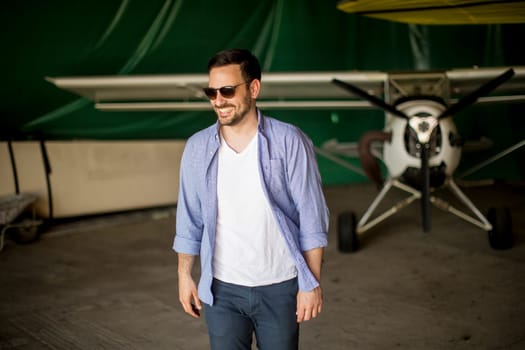 Handsome young man in the airplane hangar