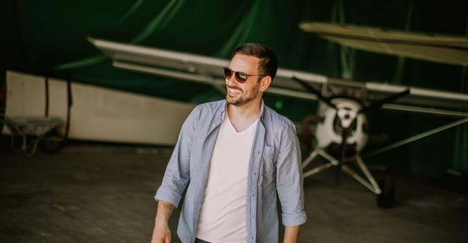 Handsome young pilot checking ultralight airplane before flight
