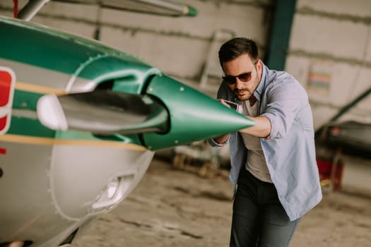 Handsome young pilot checking ultralight airplane before flight