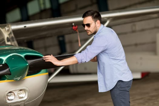 Handsome young pilot checking ultralight airplane before flight