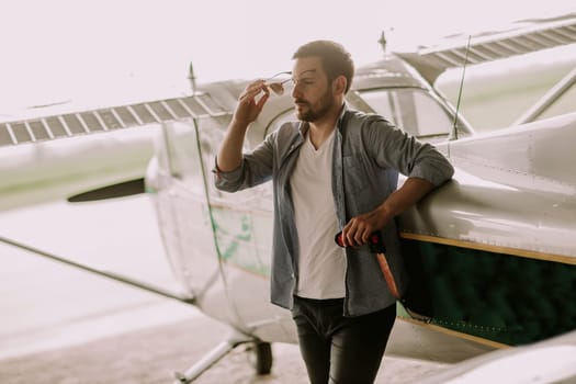 Handsome young pilot checking ultralight airplane before flight