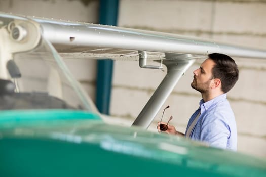 Handsome young pilot checking airplane  in the hangar