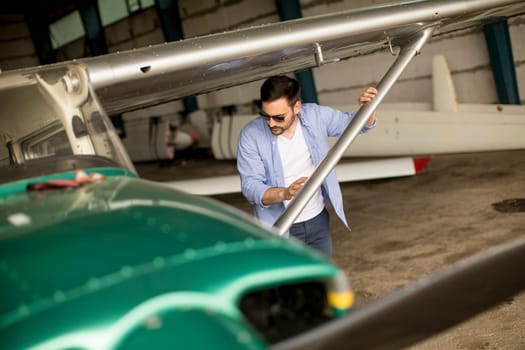 Handsome young pilot checking airplane  in the hangar