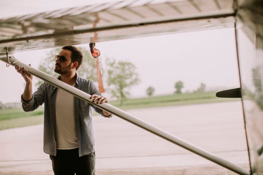 Handsome young pilot checking airplane  in the hangar
