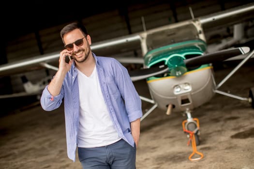 Handsome young pilot checking ultralight airplane before flight