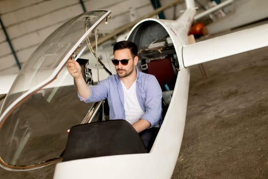 Handsome young pilot checking his ultralight airplane in the hangar before flight