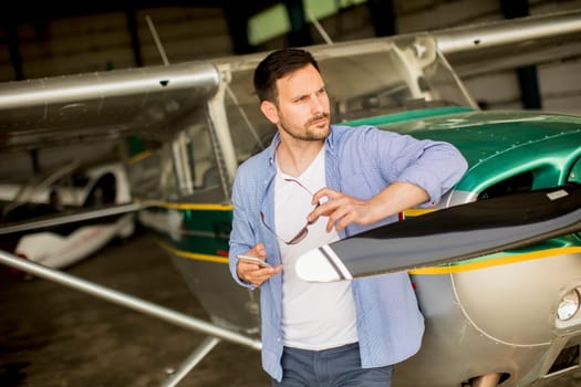 Handsome young pilot checking airplane  in the hangar