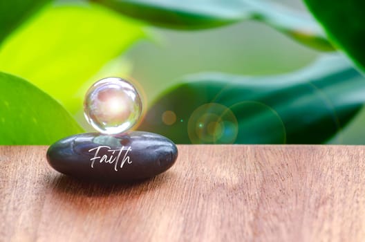 Faith text on Zen stone with bright shining glass marble. Faith concept