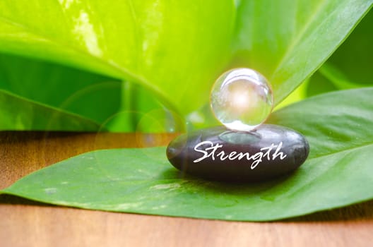 Strength text on zen stone with bright shining glass marble. Inner strength concept.