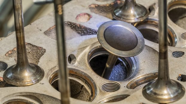 Car engine valves close up.Part of car's motor.Machinery detail of modern gasoline engine repair of cylinder head.Installing the valve of an overhauled engine.Mechanism automobile.Workshop motor car