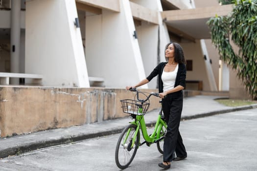 A woman strolling with her green bicycle, relishing the simple joys of life while promoting sustainable choices in her daily routine.