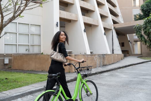With a confident smile, the woman stands next to her green bike, blending style and sustainability in a contemporary urban lifestyle.