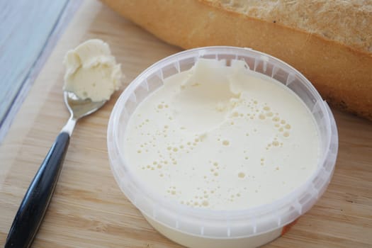 Fresh butter lies near a loaf of bread on a wooden cutting board.