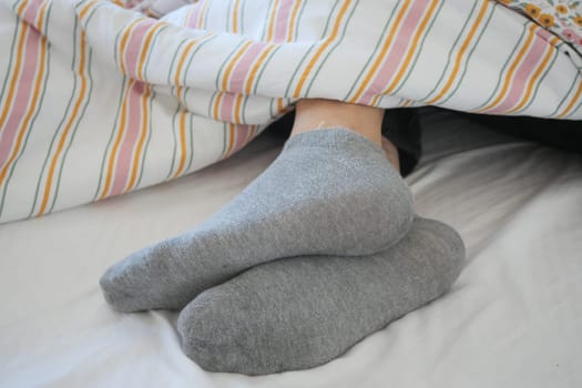 Gray socks rest comfortably on a cozy bed with colorful bedding.