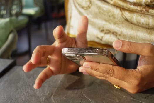 Person using a smartphone with focused gestures in a comfortable cafe.