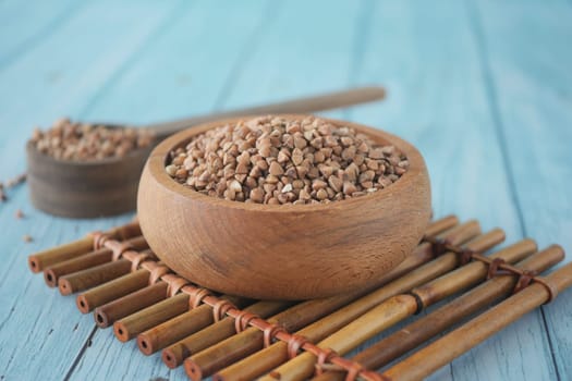 Organic buckwheat grains are displayed in a wooden bowl on bamboo.