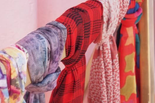 Various stylish scarves hang neatly on a wooden display rack.