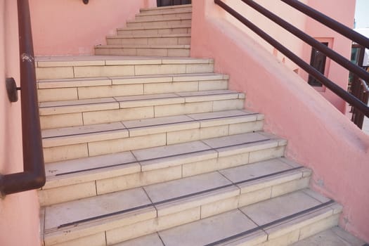 Light-colored stairs ascend towards a colorful building in daylight.