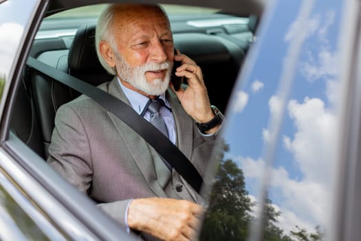Suave senior man converses on his cell during a leisurely car ride, exuding charm and confidence