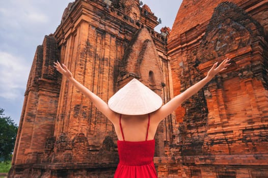 back of Asian girl tourist traveler in a Vietnamese cone hat on the Cham Towers of Po Nagar in Nha Trang in Vietnam in Asia