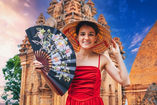 happy young woman tourist traveler in a Vietnamese hat with a fan at Po Nagar Cham Towers in Nha Trang in Vietnam in Asia