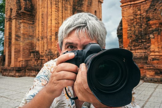 elderly man tourist traveling professional photographer with a camera takes pictures of landmarks at Po Nagar Cham Towers in Nha Trang in Vietnam in Asia