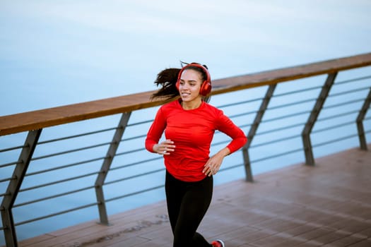 View at active young beautiful woman running on the promenade along the riverside
