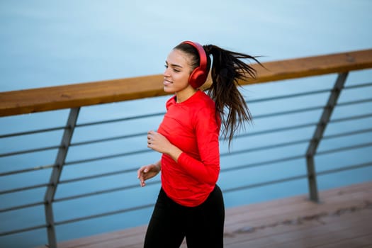 View at active young beautiful woman running on the promenade along the riverside