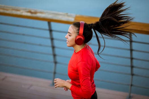 View at active young beautiful woman running on the promenade along the riverside