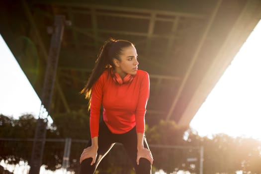 Attractive young female runner taking break after jogging outdoors