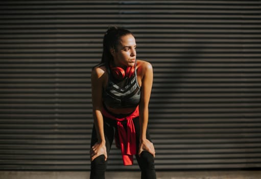 Pretty young woman takes a break after running in the urban area