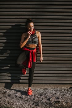 Pretty young woman takes a break after running in the urban area