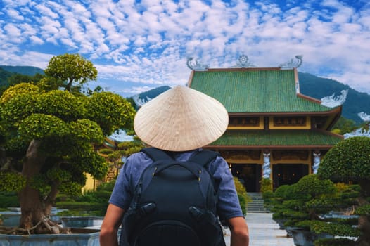 back of a male tourist traveler at a Buddhist temple at the Linh Ung Pagoda in Da Nang in Vietnam. The concept of travel and tourism in Asia