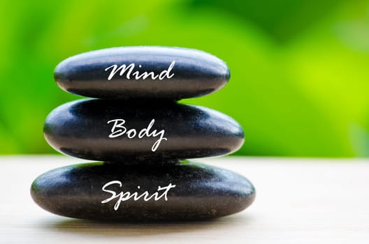 Close up of black Zen stones with Mind Body and Spirit text on the stones. Zen and peaceful concept.