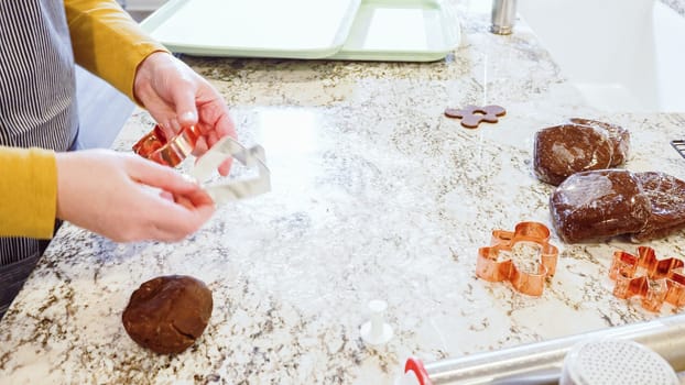 Using various festive cookie cutters, we're cutting out charming gingerbread cookies from the rolled dough on the sleek marble counter, bringing holiday cheer to the modern kitchen.