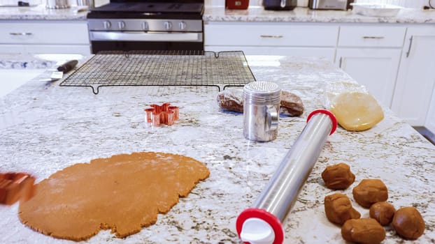 Using an adjustable rolling pin to roll out gingerbread cookie dough on the elegant marble counter in a modern kitchen, getting ready for festive holiday baking.