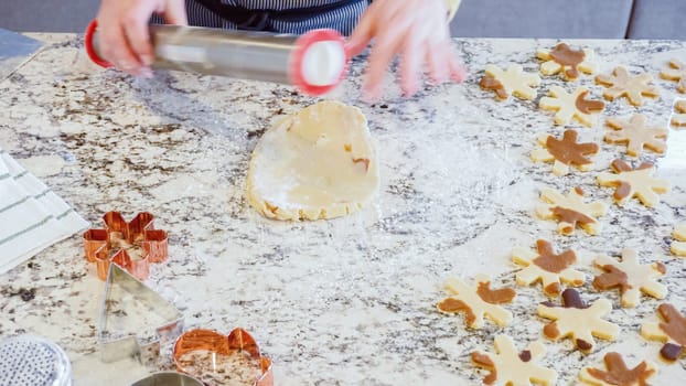 Using an adjustable rolling pin to roll out gingerbread cookie dough on the elegant marble counter in a modern kitchen, getting ready for festive holiday baking.