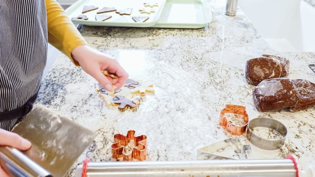 Using various festive cookie cutters, we're cutting out charming gingerbread cookies from the rolled dough on the sleek marble counter, bringing holiday cheer to the modern kitchen.