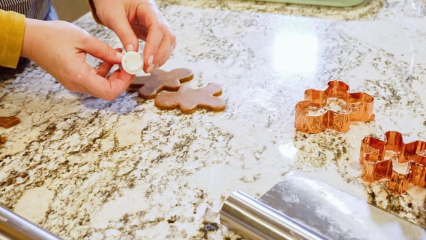 Using various festive cookie cutters, we're cutting out charming gingerbread cookies from the rolled dough on the sleek marble counter, bringing holiday cheer to the modern kitchen.