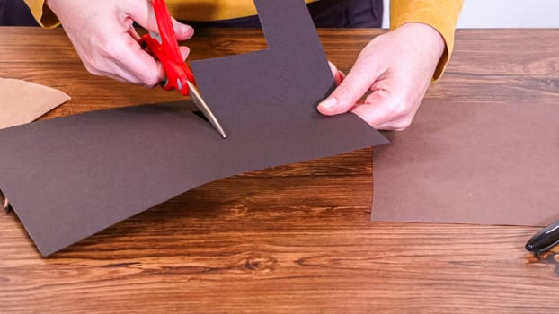 Step by step. Teacher guides online class through making a paper puppet from a brown bag, creatively using a wooden surface as a workspace.