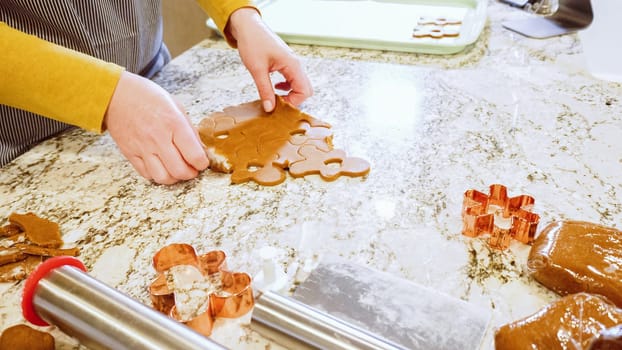 Using various festive cookie cutters, we're cutting out charming gingerbread cookies from the rolled dough on the sleek marble counter, bringing holiday cheer to the modern kitchen.