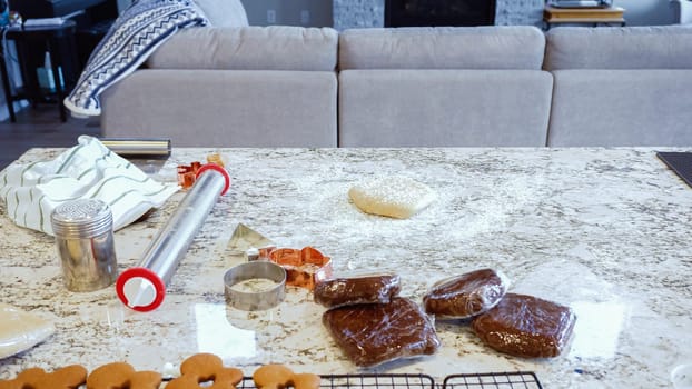 Using an adjustable rolling pin to roll out gingerbread cookie dough on the elegant marble counter in a modern kitchen, getting ready for festive holiday baking.