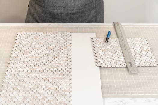 In the process of mounting peel and stick mosaic tiles onto a foam board, perfect for enhancing a food photography studio's aesthetic.