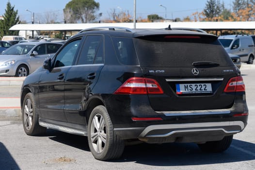 Gaziveren Cyprus -15.03.2025 A sleek black SUV rests amid a vibrant parking lot on a clear day, surrounded by lush greenery and other parked cars.