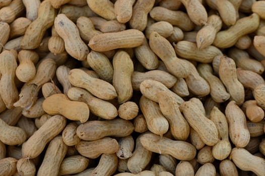 A collection of earthy peanuts piled high, showcasing their natural textures under warm sunlight at the market.