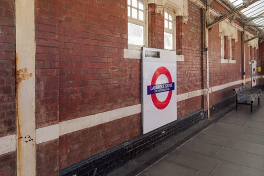 London, UK Ladbroke Grove Tube station empty platform with brick walls, benches and signage.
