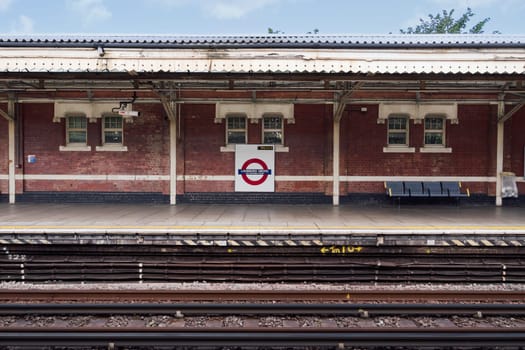 London, UK Ladbroke Grove Tube station empty platform with brick walls, benches and signage.